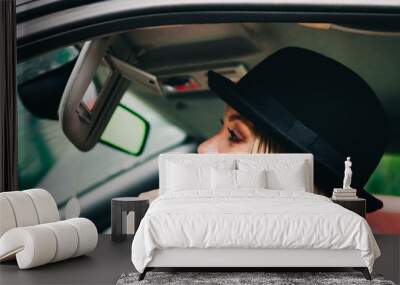 Young woman applying lipstick in car Wall mural