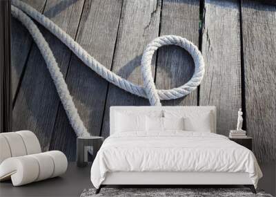 Ship ropes tied to knot isolated on wooden background closeup at the port. Wall mural