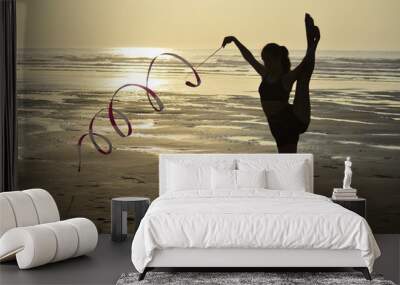 Sunset with girl on the beach doing gymnastics Wall mural