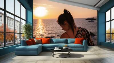 Unrecognizable young woman on her back in a magical and beautiful sunset in Mykonos Wall mural