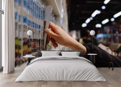 A person is reaching for a book on a shelf in a store Wall mural