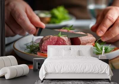 A person skillfully slices a juicy piece of beef on a white plate surrounded by fresh vegetables and fragrant herbs, highlighting a culinary experience focused on fresh ingredients Wall mural