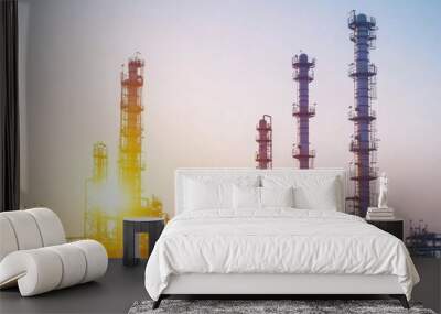 At dawn, sunlight breaks over an industrial oil processing plant with tall smokestacks, casting long shadows and illuminating the scene against a clear sky Wall mural