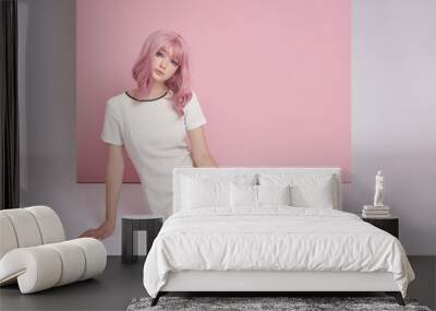 Beautiful girl with long pink hair sitting on the floor, hair coloring. Cute woman on a pink background in a short white dress. Colored hair, perfect hairstyle Wall mural