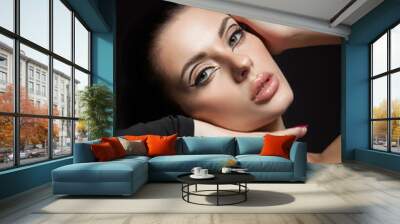 Classic makeup on woman face, beautiful big eyes. Fashion Perfect makeup, expressive eyes on girl face, smooth black eyebrows, licked brunette hair. Portrait woman on dark background Wall mural