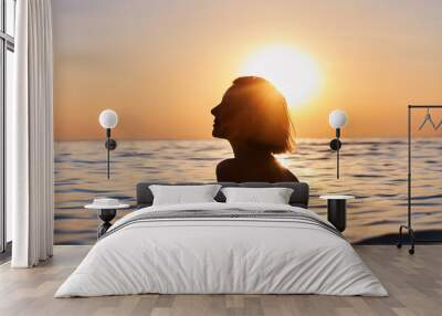 silhouette of woman relaxing in water at sunset, in the style of emotional sensitivity, serene faces, backlight, joyful and optimistic Wall mural