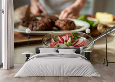 Bowl with fresh radish salad marinated with olive oil and parsley on kitchen table Wall mural