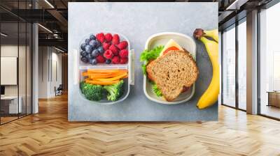 School lunch box with sandwich vegetables water almonds and fruits on grey table healthy Wall mural