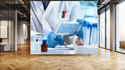 Scientist working with samples panel microplate and registering data for diseases diagnostic in the laboratory. Researcher Sample Analysis and writes down the data result of for elisa analysis Wall mural