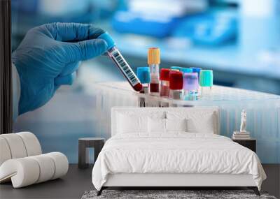 Technician holding blood tube test in the research laboratory / doctor hand taking a blood sample tube from a rack with machines of analysis in the lab background  Wall mural