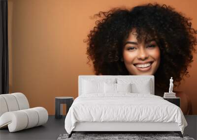 Beautiful girl smiling with curly hair and clean healthy skin on an orange background with copy space Wall mural