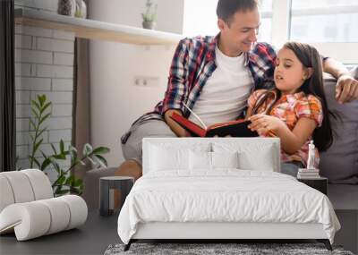 a young father with his little daughter reads the Bible Wall mural