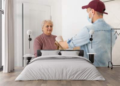 An elderly woman in a medical mask stays at home. Food delivery to the elderly Wall mural