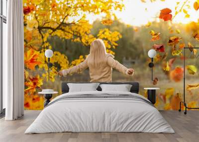 Beautiful girl walking outdoors in autumn. Smiling girl collects yellow leaves in autumn. Young woman enjoying autumn weather. Wall mural