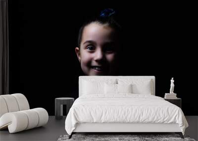 Closeup portrait of serious little girl isolated on black background Wall mural