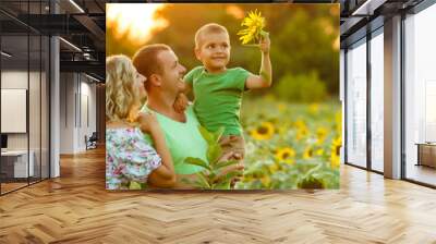 Happy family having fun in the field of sunflowers. Father hugs his son. Mother holding sunflower. outdoor shot Wall mural