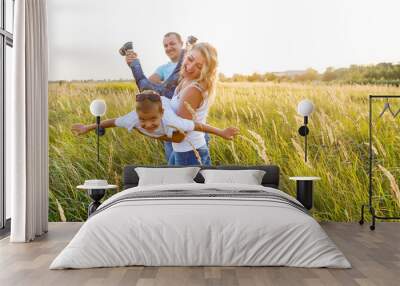 Happy family playing in a wheat field. Wall mural