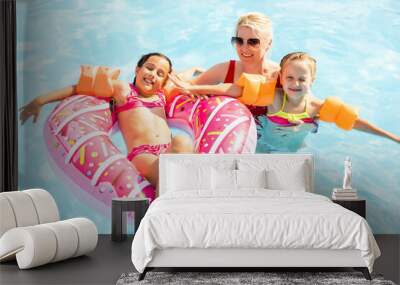 Happy family playing in blue water of swimming pool on a tropical resort at the sea. Summer vacations concept. Wall mural