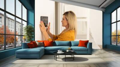 Iot Smart Home Concept - rear view of asian woman ask digital tablet to set temperature of air conditioner more higher by voice at home and all the electric meter in house getting energy-efficient. Wall mural