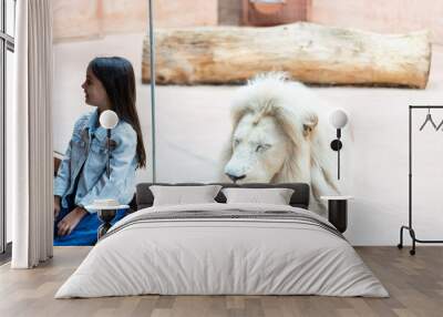 little girl and lion behind glass at the zoo Wall mural