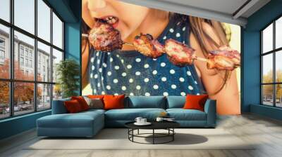 Little girl bites a shish kebab. Wall mural