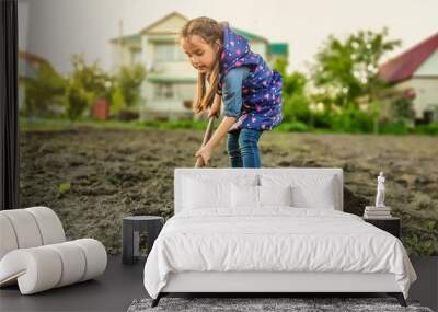 Little girl on a sunny day in the garden with a hoe Wall mural