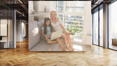 Little girl studying online using her laptop at home Wall mural