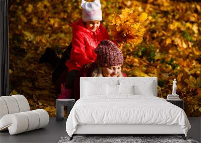 Mother and daughter having fun in the autumn park among the falling leaves. Wall mural