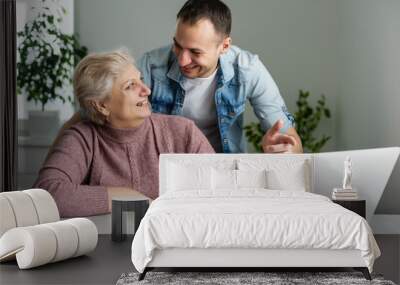 Portrait of a senior woman and a man in front of a laptop computer Wall mural