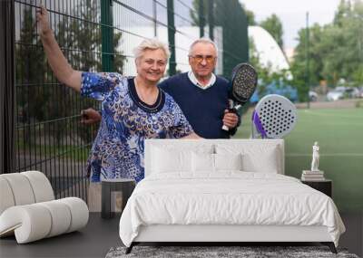 Portrait of sporty fit senior woman playing padel on open court on summer day, ready to hit ball. Health and active lifestyle concept.. Wall mural