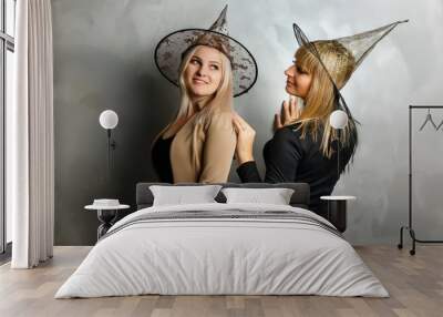 Portrait of two happy young women in black witch halloween costumes on party over gray background. Wall mural