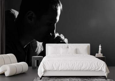 Religious young man praying to God on dark background, black and white effect Wall mural