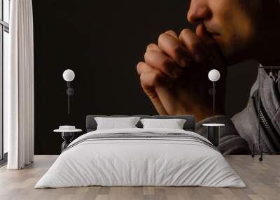 Religious young man praying to God on dark background, black and white effect Wall mural