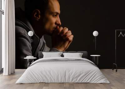 Religious young man praying to God on dark background, black and white effect Wall mural