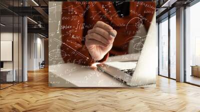 Science and education concept. Illustration of basic physics and mathematics formulas and man working on laptop at table, closeup Wall mural