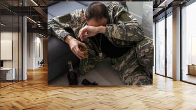 Serious anxious and nervous military man suffers from depression while sitting alone at home. Pensive man in military uniform sitting on sofa propping his head with his hands. PTSD concept. Wall mural