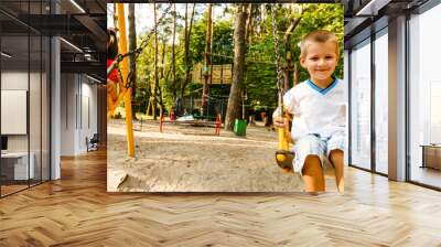 Sister and brother in playground swing outdoors Wall mural