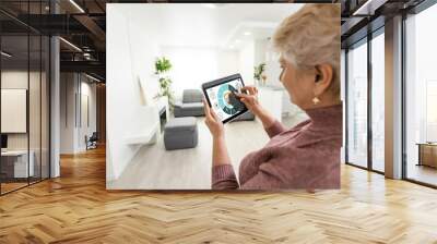 technology, automation and efficiency concept - smiling senior woman in glasses with tablet computer using smart home app over grey background Wall mural