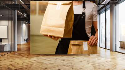 Two boxes with fast food being carried by delivery man in uniform for one of clients Wall mural