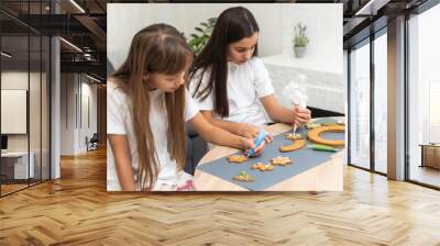 Two girls sisters are playing around in the kitchen after making Christmas cookies, they draw with flour on the table and on their faces. Christmas, New Year concept Wall mural