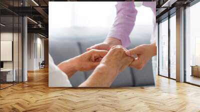 Young doctor holding hand of elderly woman on light background Wall mural