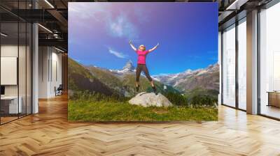 Young girl holds hands up against the sky and mountain Wall mural