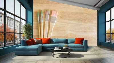 Two rounded and two flat painting brushes on wooden background whith free space on the right Wall mural