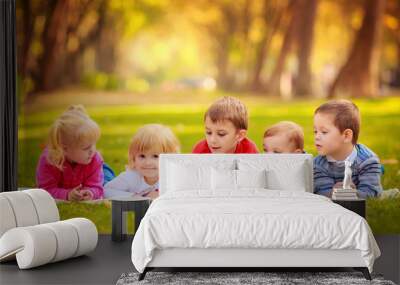 children in nature. reading a book outdoors lying on the grass Wall mural