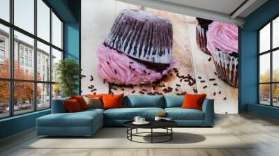 cupcake with pink frosting fallen upside down with messed chocolate sprinkles . Wall mural