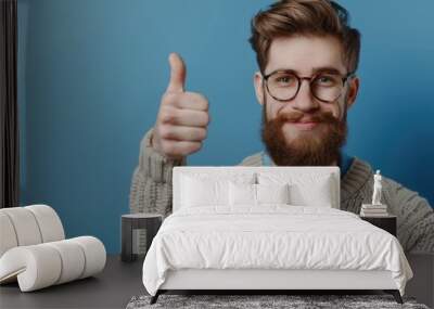 Young man in casual attire and glasses giving thumbs up. Wall mural