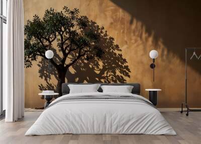 A solitary tree silhouetted against a warm sunset, bathed in golden and orange hues. Wall mural