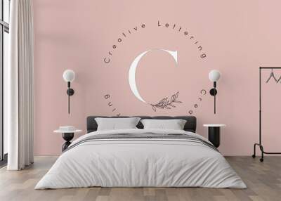 White Letter C Logo with circle lettering design and outline leaves and pastel backgound. Wall mural