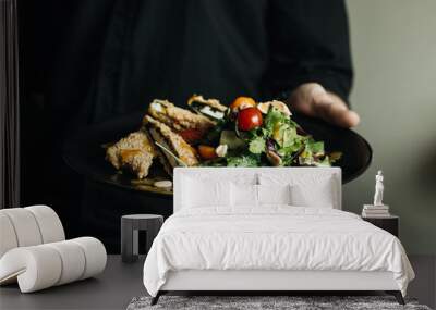 Man holding black plate with fresh green salad Wall mural