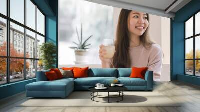 Asian woman drinking juice and resting at home Wall mural